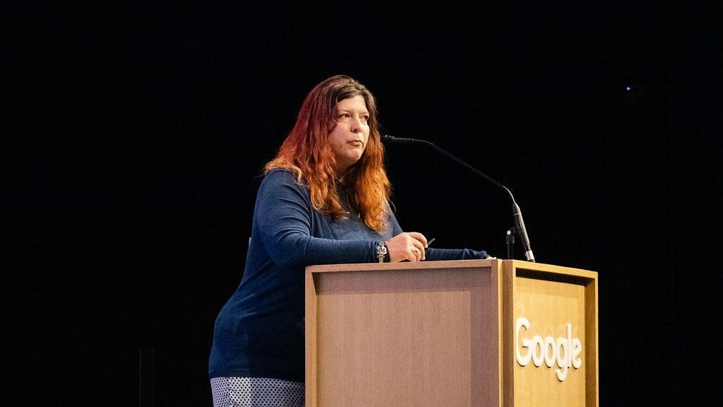 Manu Heim steht vor dem Rednerpult. Der Hintergrund ist schwarz.