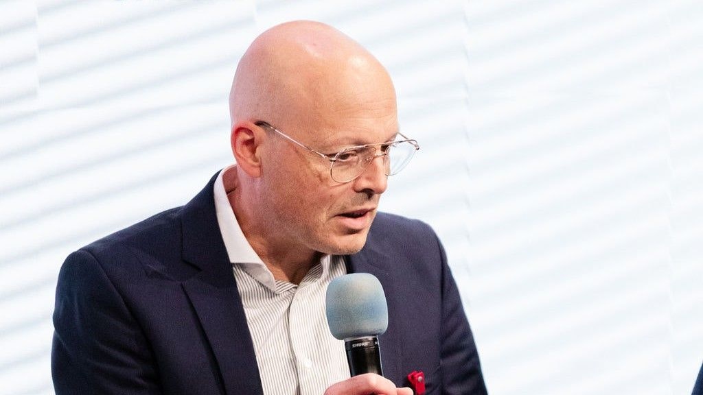 Markus Riesch parla al microfono. Lo sfondo è bianco.